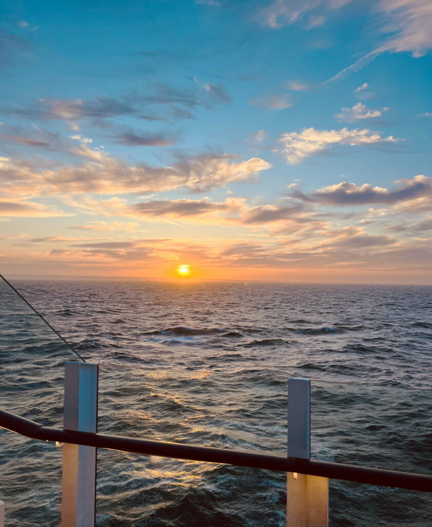 Der Blick vom Kreuzfahrtschiff aus auf das offene Meer über dem die Sonne langsam untergeht.