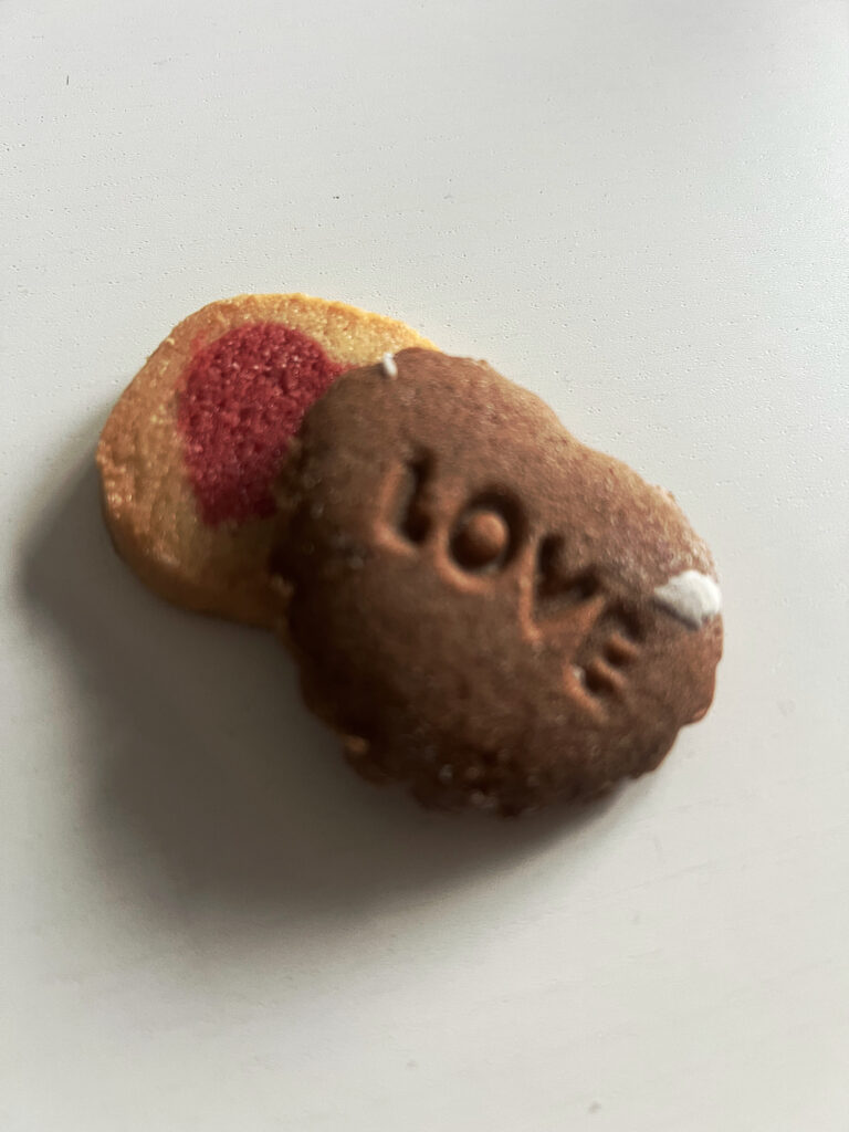 Weihnachtszeit ist Plätzchenzeit, hier zwei Stück aus der eigenen Herstellung. Eines ziert ein Herz drauf, das dunklere und größere den Schriftzug "Love".